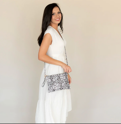 Woman in a white dress holding a snakeskin-pattern wristlet