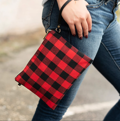 Red and black checked wristlet held beside jeans