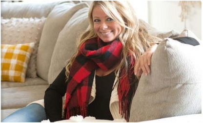 Woman wearing a red and black buffalo check scarf with fringed ends.