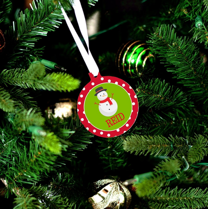 Snowman Christmas ornament personalized with Reid hanging from a white ribbon on a Christmas tree