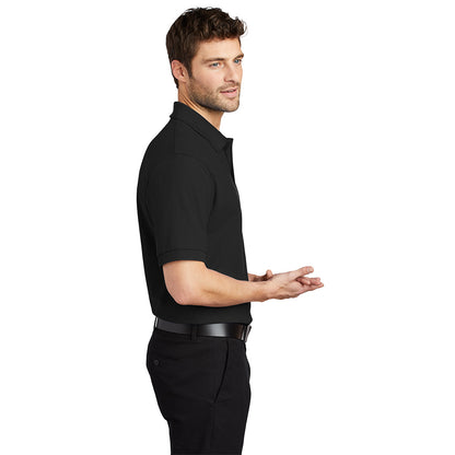 Man in profile wearing a black short-sleeved polo shirt and black pants.