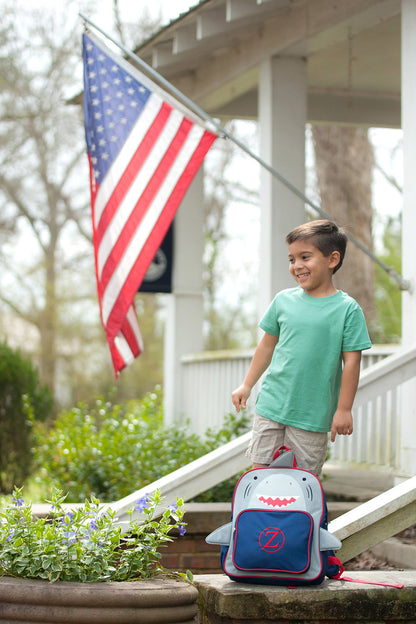 Child holding a shark backpack on outdoor steps