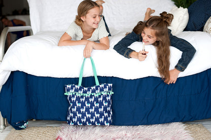 Navy llama tote beside two children reading on a bed