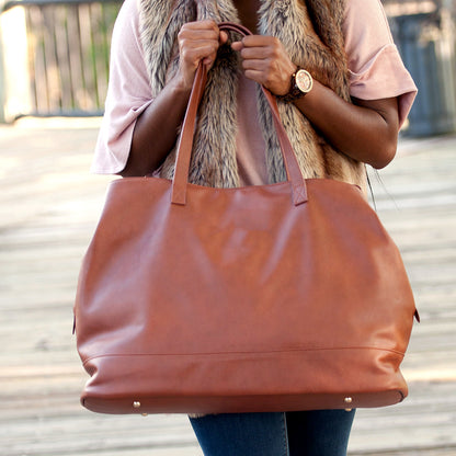 Close-up of a camel Cambridge travel tote held by its handles