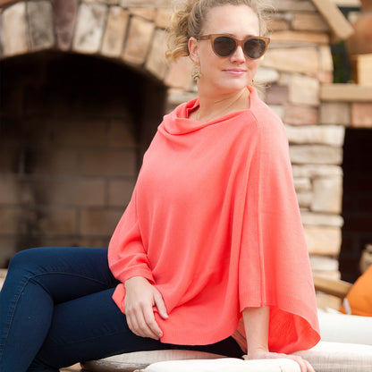 Woman seated in a coral Chelsea poncho