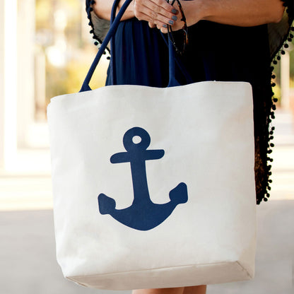 Light tote with a navy anchor and navy handles held in front of the body
