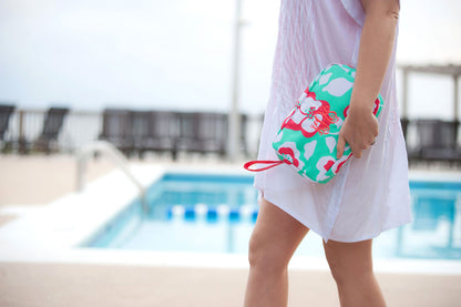Woman carrying a mint floral cosmetic pouch beside a pool