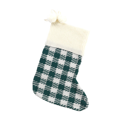 Green and cream houndstooth knit Christmas stocking with cream cuff and pom-poms on white
