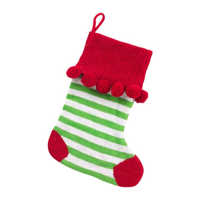Green and white striped knit stocking with red cuff, heel, toe and pom-poms on white