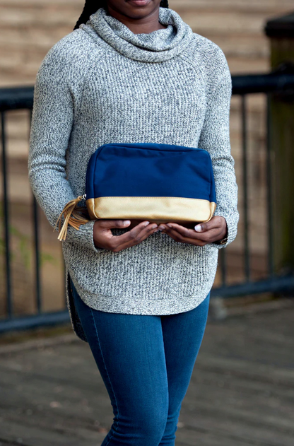 Woman holding a navy Cabana cosmetic bag with gold-colored lower panel