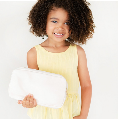 Child holding a cream rectangular accessory pouch