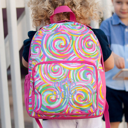 Child wearing a multicolor swirl-print backpack with pink trim