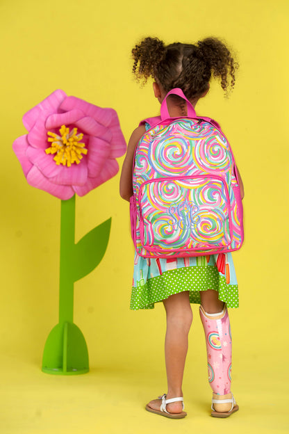 Back view of a child wearing a swirl-print backpack beside a flower prop