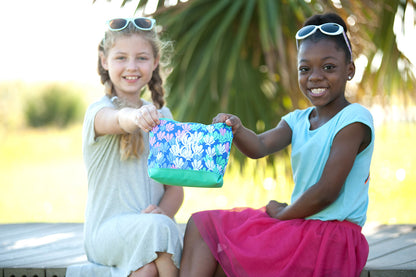 Two children holding a mermaid-tail-print accessory pouch outdoors