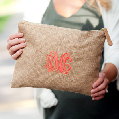 Natural burlap-style pouch with a pink monogram held in both hands