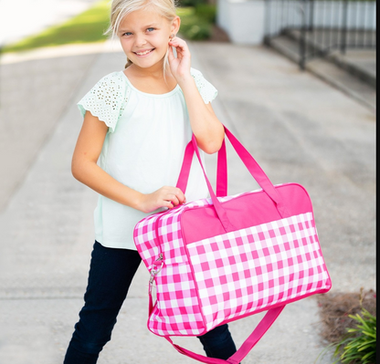 Child carrying a pink checked travel bag