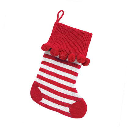 Red and white striped knit stocking with red cuff, heel, toe and pom-poms on white